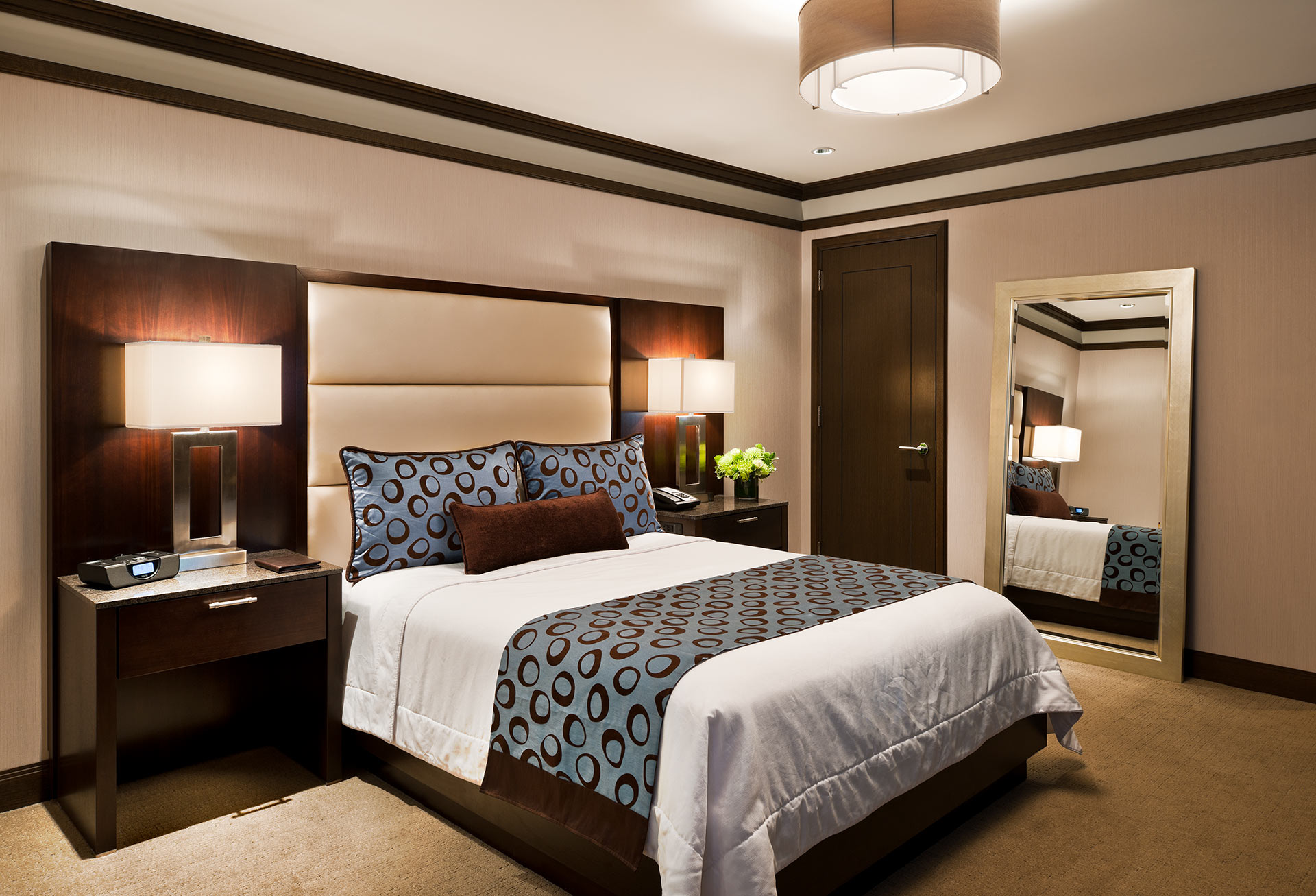 A wide view of a hotel room with a king-sized bed, two nightstands, and a mirror.